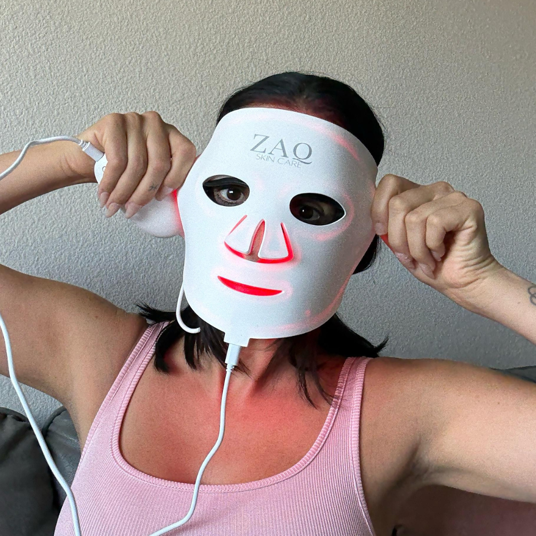 Person wearing a ZAQ LED face mask with visible red light on a plain background