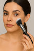 Woman applying makeup with a brush on a neutral background