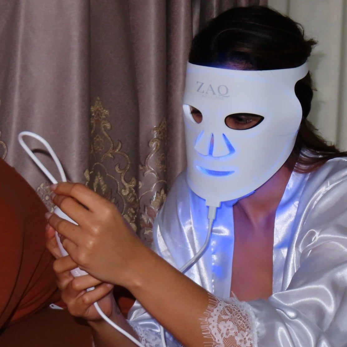 Person wearing a LED face mask in a room with curtains.