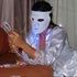 Person wearing a LED face mask in a room with curtains.