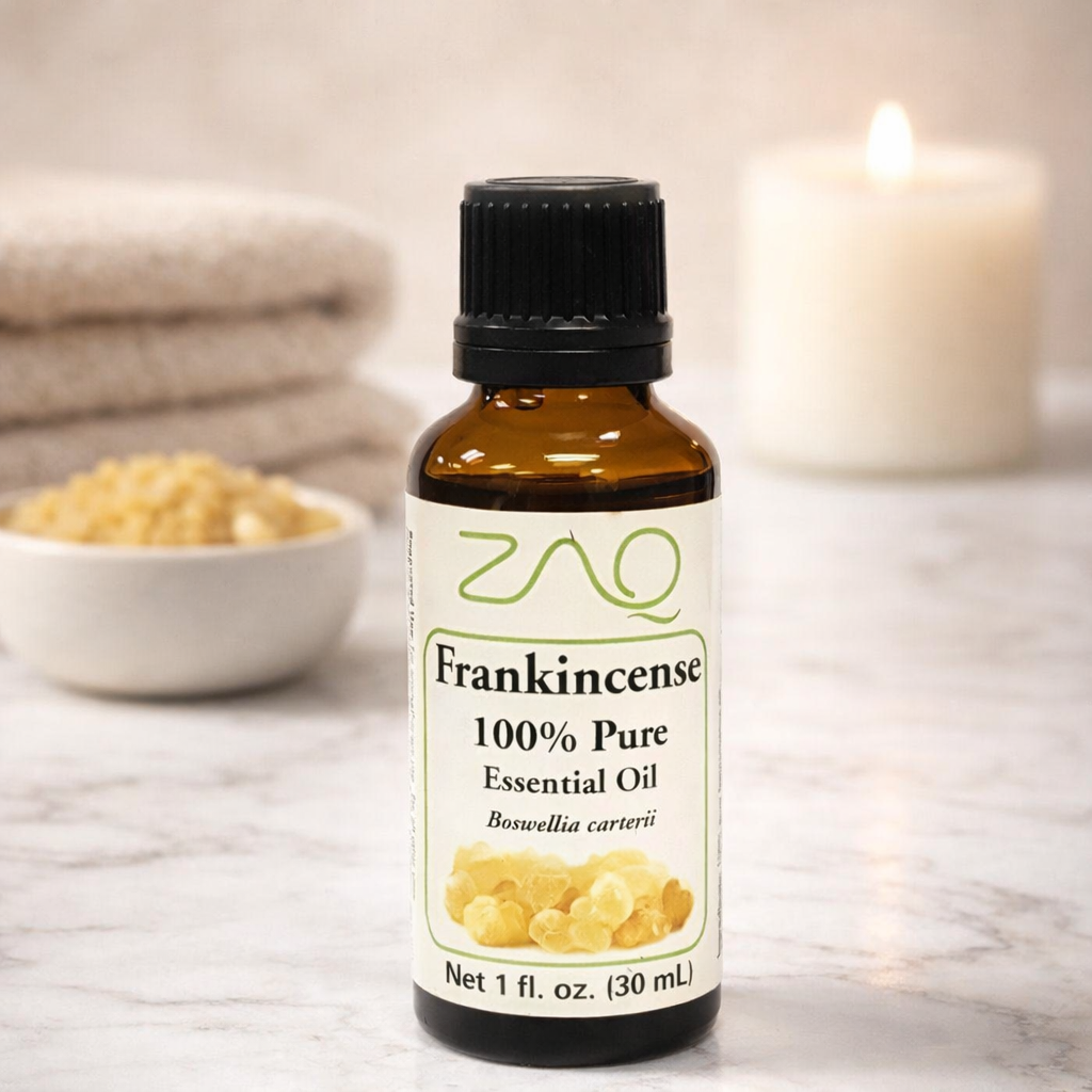 Bottle of ZAO Frankincense essential oil on a marble surface with a candle and bowl in the background.
