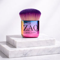 Multicolored makeup brush with 'ZAQ' branding on a white marble surface