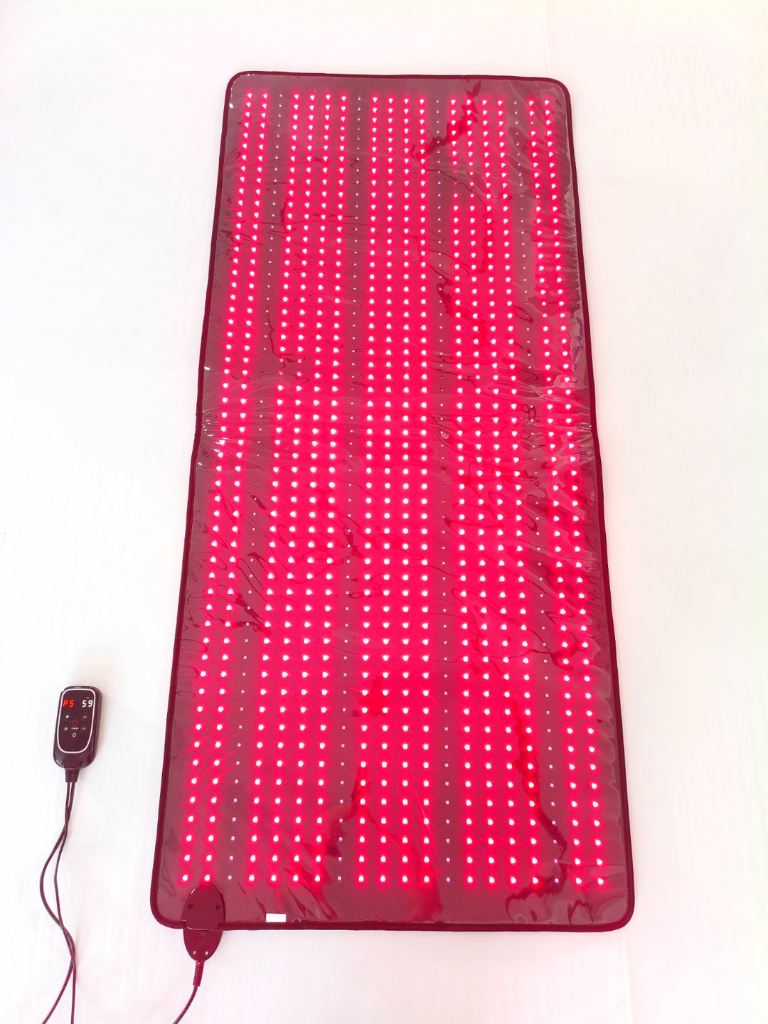 Red light therapy mat with control device on a white background
