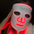 Person wearing a LED face mask with red light on a dark background