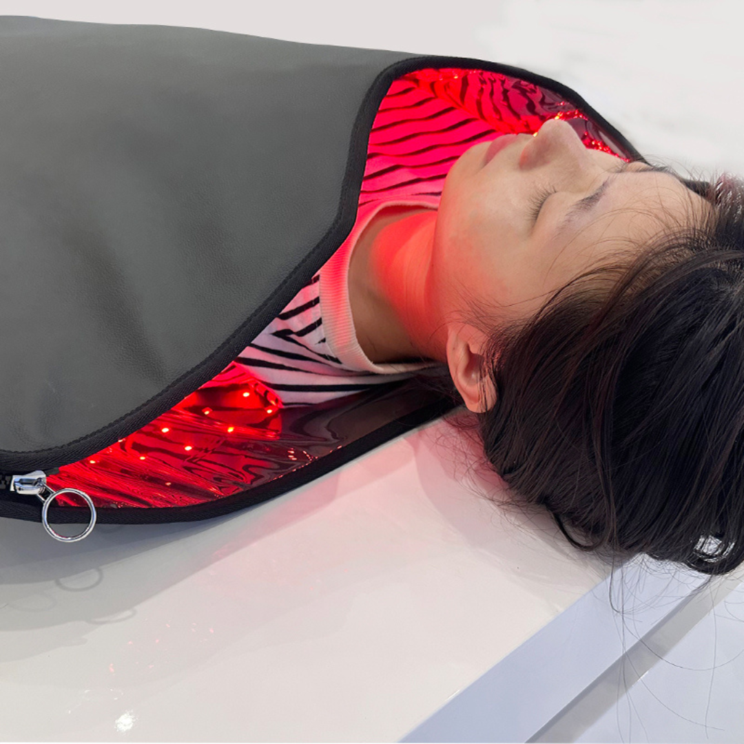 Person lying on a red light therapy mat with glowing red lights.