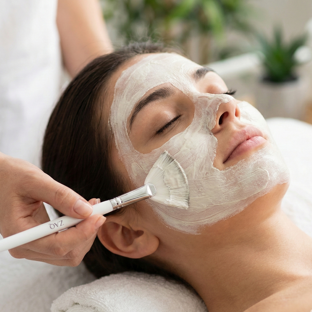 Person receiving a facial mask treatment with a brush applicator.