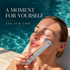 A woman relaxes by a swimming pool while using a silver ZAQ skin care device on her face. The text 'A MOMENT FOR YOURSELF' and 'ZAQ SKIN CARE' is displayed on the top left.