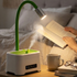 Person reading a book with a green desk lamp on a bedside table in a bedroom.