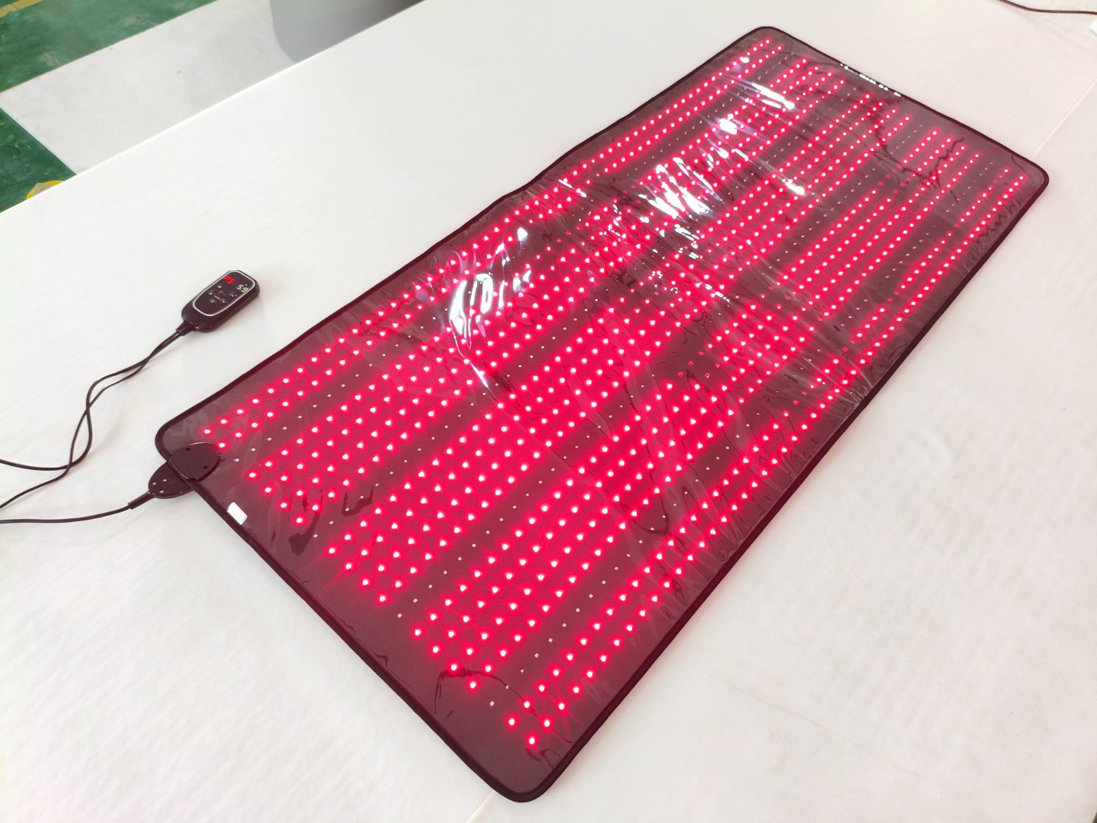 Red LED mat with power cable on a white surface