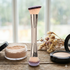 Makeup brush with a container of powder on a wooden surface with a blurred natural background